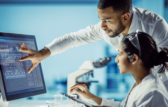 Two medical professionals assess patient data on a computer screen.